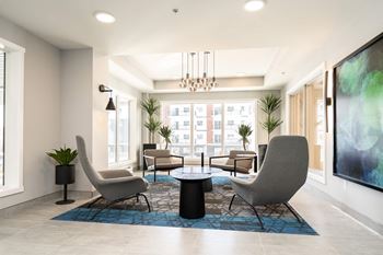 a lounge area with chairs and tables and a large window